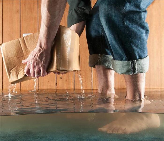 barefoot man scooping water from flooded floor